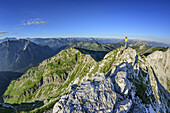 Woman hiking on rocky ridge, Lechtal Alps and Ammergau Alps in background, Ammergauer Hochplatte, Ammergau Alps, East Allgaeu, Allgaeu, Swabia, Bavaria, Germany