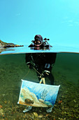 The assistant shows a picture of the artist written by under water artist Yuriy Alexeev (Yuri Alekseev). Lake Baikal, Listvyanka, Irkutsky District, Irkutsk Oblast, Siberia, Russia, Eurasia.