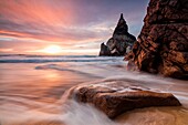 The fiery sky at sunset is reflected on the ocean waves and cliffs Praia da Ursa Cabo da Roca Colares Sintra Portugal Europe.
