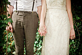 Mid-section of a bride and groom holding hands at a simple wedding ceremony