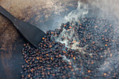 'Coffee beans being roasted by hand in a wok by the coffee pickers; Sumatra, Indonesia'