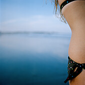 Torso einer Frau im Bikini mit Meer im Hintergrund