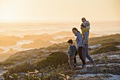 Happy young family walking on the beach at sunset