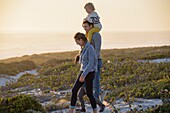 Happy young family walking on the beach at sunset