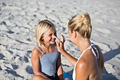 Woman applying sun screen on her daughter nose