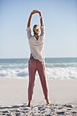 Beautiful young woman doing yoga on sunny beach