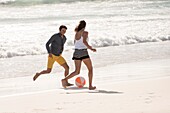 Happy young couple playing with a beach ball