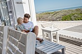 Happy father and son reading a book on porch