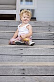 Cute baby boy sitting on steps with toy