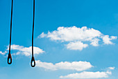 Steel ropes with hooks hang from a crane in front of blue sky with cumulus clouds, Hamburg, Germany