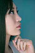 Woman looking away in thought with hand under chin