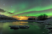 The Northern Lights illuminates the icy landscape in Svensby Lyngen Alps Troms?© Lapland Norway Europe