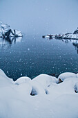 Heavy snowfall on the fishing village and the icy sea Nusfjord Lofoten Islands Norway Europe