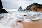 Ocean waves crashing on the sandy beach of Praia da Ursa surrounded by cliffs Cabo da Roca Colares Sintra Portugal Europe