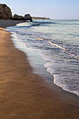 The rising sun illuminates the fine sand bathed by the blue ocean Praia do Vau Portimao Faro district Algarve Portugal Europe