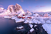 Pink sunrise on snowy peaks surrounded by the frozen sea around the village of Hamnoy Nordland Lofoten Islands Norway Europe