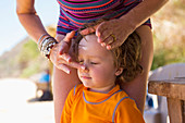 Caucasian mother applying sunscreen to face of son