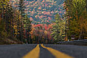 A road along a bright mix of reds, oranges, yellows and greens in the White Mountains of New Hampshire.
