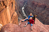 A mother and daughter and their dog sitting on the edge of Toroweap Overlook above the Colorado River, Grand Canyon National Park, Fredonia, Arizona.