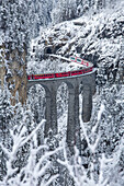 Bernina Express train passes on Landwasser Viadukt Filisur Canton of Graubünden Switzerland Europe.