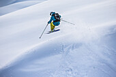 Junger Skifahrer springt im Tiefschnee abseits der Piste, Andermatt, Uri, Schweiz