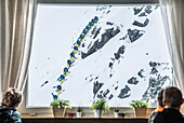 Gäste beobachten einen Skifahrer bei einem Sprung durchs Fenster, Andermatt, Uri, Schweiz