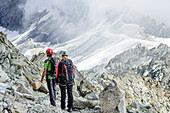 Mann und Frau steigen vom Klettersteig Sentiero dei Fiori ab auf Gletscher zu, Sentiero dei Fiori, Adamello-Presanella-Gruppe, Trentino, Italien