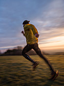 Young man running over a meadow during sunrise, Allgaeu, Bavaria, Germany