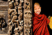 Myanmar (Burma), Mandalay Division, Mandalay, Shwe Nan Daw temple, novice Shin Aung Lwin (11 year old) in front of the carved panels made of teak