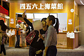 Two young women take selfie photograph with cotton candy outside food stall at Macau Food Festival, Macau, Macau, China