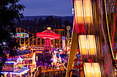 Blurred lights of ferris wheel at Aschaffenburger Volksfest beerfest and amusement park at dusk, Aschaffenburg, Spessart-Mainland, Bavaria, Germany