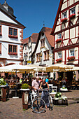 Couple with bicycles look at map in front Gasthaus Herzog von Franken restaurant in Altstadt old town, Lohr am Main, Spessart-Mainland, Bavaria, Germany