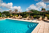Young woman relaxes by swimming pool at Agroturisme Sa Carrotja finca hotel, ses Salines, Mallorca, Balearic Islands, Spain
