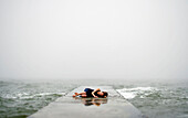 Caucasian woman laying on dock in ocean waves