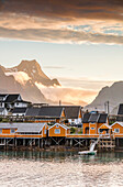 Sunset on the fishing village framed by rocky peaks and sea, Sakrisoya, Nordland county, Lofoten Islands, Arctic, Northern Norway, Scandinavia, Europe