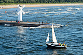 A sail boat passing the lighthouse at harbor in Swinoujscie, Poland