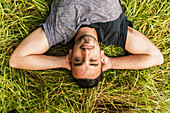 Close up of a man laying on the grass with his hands behind his head, Reigate, England