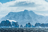 Icebergs and snow covered rock formations along the Antarctic coastline, Antarctica