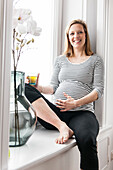 pregnant woman sitting at the window drinking tea, Hamburg, north Germany, Germany