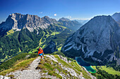 Woman hiking towards Ehrwalder Sonnenspitze, Wetterstein range with Zugspitze and lake Seebensee in background, Ehrwalder Sonnenspitze, Mieming range, Tyrol, Austria