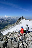 Mann und Frau sitzen am Gipfel der Reichenspitze, Reichenspitze, Zillergrund, Reichenspitzgruppe, Zillertaler Alpen, Tirol, Österreich