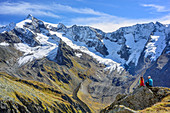 Zwei Personen beim Wandern sitzen auf Fels und blicken auf Dreiherrenspitze, Naturpark Zillertaler Alpen, Dreiländertour, Zillertaler Alpen, Südtirol, Italien