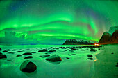 Aurora borealis, Polarlicht über Strand mit Felsen und Bergen, Lofoten, Norland, Norwegen
