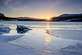 Niedrig stehende Sonne über vereistem See, Vasterbotten, Schweden