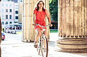 Young woman bicycling on Königs Plaza in Munich, Bavaria, Germany