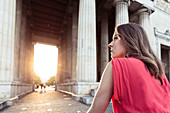 Junge Frau in der Abendsonne unter den Propyläen am Königsplatz in München, Bayern, Deutschland