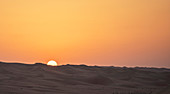 Sunrise over sand dunes in desert landscape