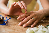 Hands of Hispanic woman wearing rings near flowers and sunglasses