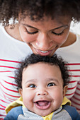 Smiling mother leaning chin on head of baby son