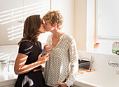 Caucasian lesbian couple kissing in kitchen